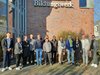 Gruppenfoto von 13 Personen vor einem Gebäude mit dem Schriftzug 'Bildungswerk' bei sonnigem Wetter